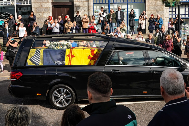 People gather in tribute as the cortege carrying the coffin of the late Queen Elizabeth II passes by on September 11, 2022 in Banchory, United Kingdom.