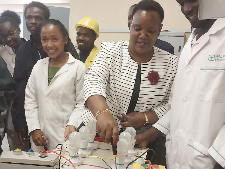 Labour and Skills Development CS Florence Bore (C) trying her hand on practicals during her familiarization tour of NITA in Athi River, Machakos County on Tuesday, February 14, 2023.