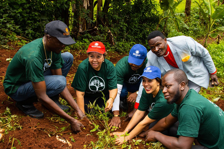 The founder and the CEO of Revitalize Homes and Gardens Susan Rodrigues (red cap) leads her officials to plant a tree in Kiambu county.