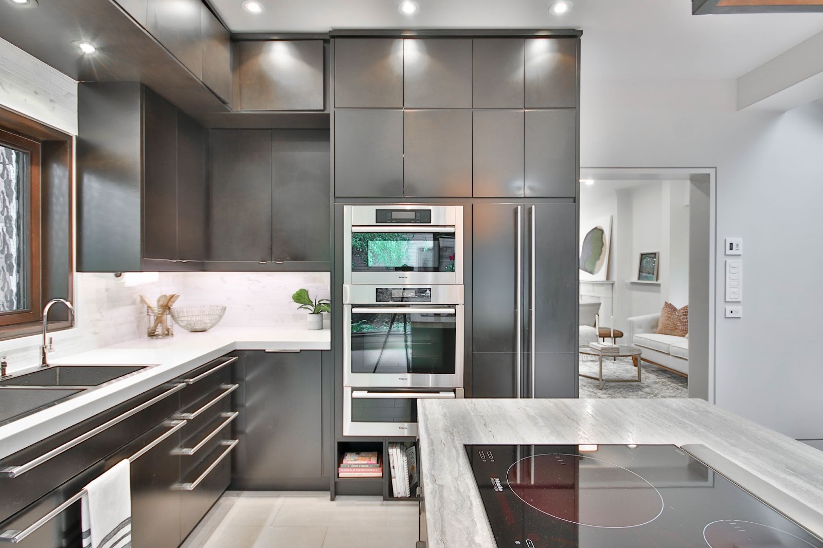 Modern kitchen with white walls, dark grey cabinets and high-end appliances.