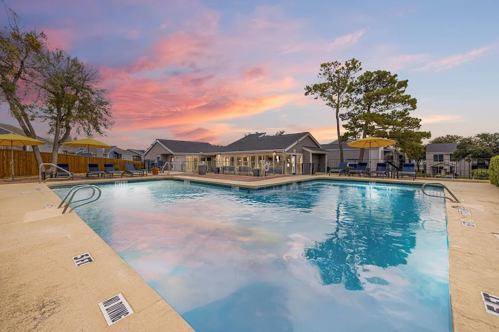 Community swimming pool with clubhouse in the background at dusk.