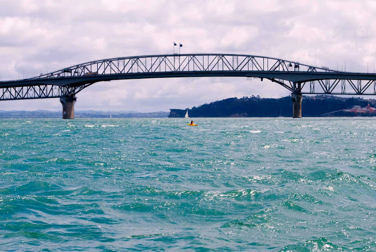 A kayaker under Auckland Harbour Bridge in New Zealand. 