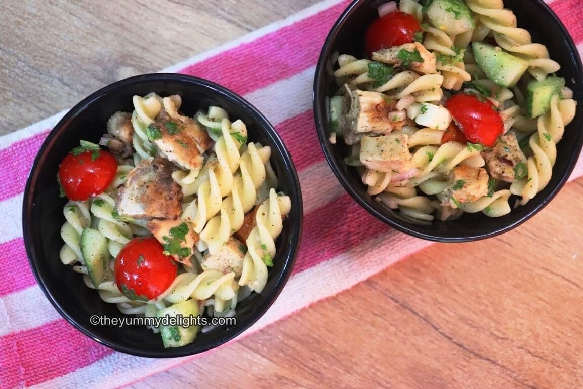 image of lemon pasta salad with chicken in a black bowl.