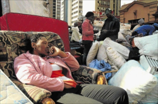 A picture of utter despair is written in the face of a woman in the streets with her belongings after being evicted by the Red Ants, which are known for their forceful removal of people, in one of the images that form part of exhibition. The photos were taken at the Monis Mansions in Johannesburg CBD PHOTO: MOSHE SEKETE