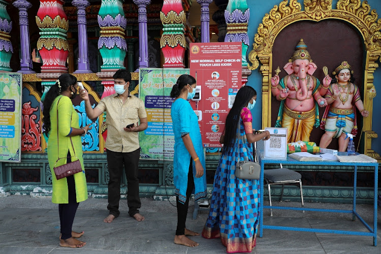 A worker checks the temperature of a devotee outside a temple, during the Hindu festival of Diwali amid the coronavirus disease outbreak in Kuala Lumpur, Malaysia on November 14 2020.