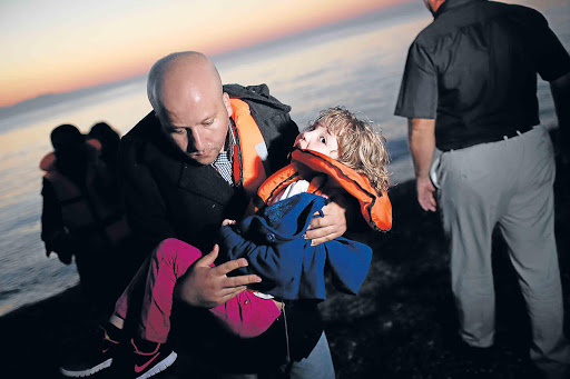 SEEKING REFUGE: A migrant family from Syria arrives as the sun rises on the beach on the island of Kos, Greece after crossing the Aegean Sea from Turkey on Friday. Migrants from the Middle East and North Africa continue to flood into Europe at a rate that marks the largest migration since World War 2 Picture: GETTY IMAGES