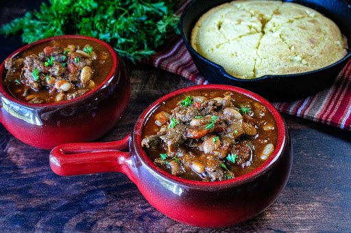 Two bowls of Cindy's Tipsy Beef Chili with cornbread on the side.