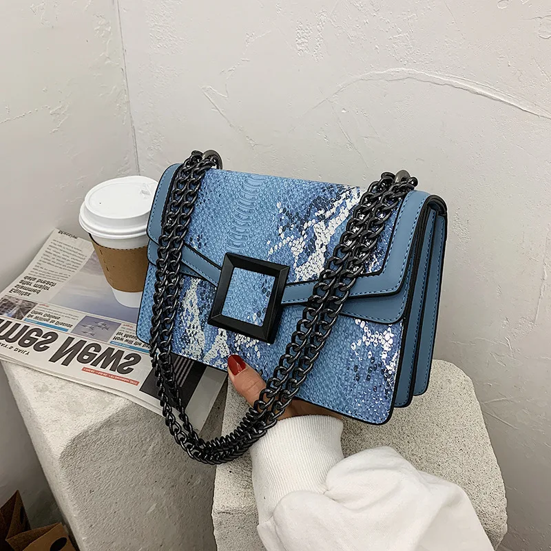 Sac bandoulière tendance à imprimé serpent et chaîne, porté à une épaule. Un sac moderne pour un look stylé et élégant, parfait pour toutes occasions.