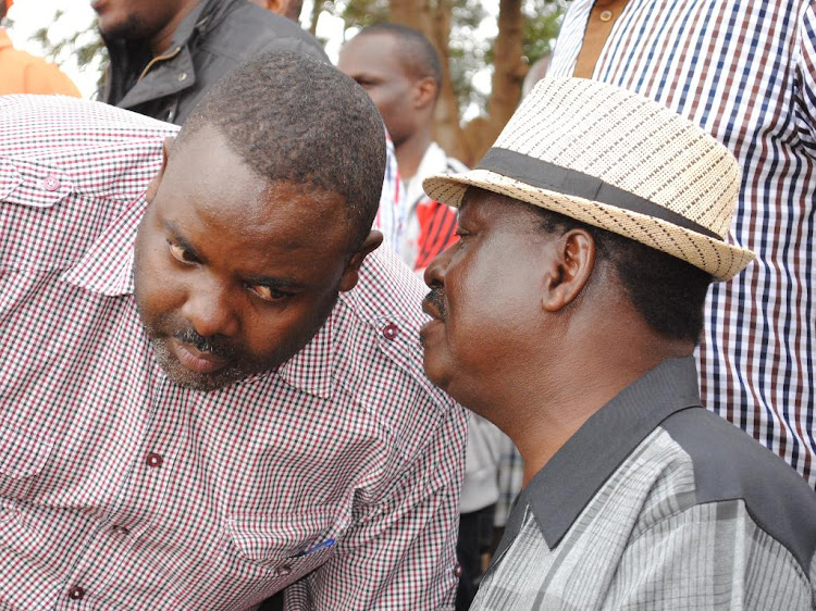 ODM leader Raila Odinga consults with Makadara MP George Aladwa during a past rally at the Kamukunji grounds in Kibra.