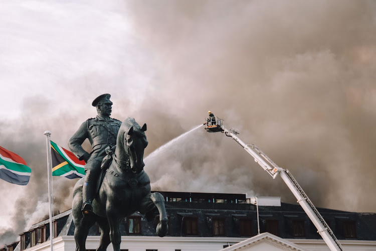 Firefighters douse the flames at parliament. File photo.