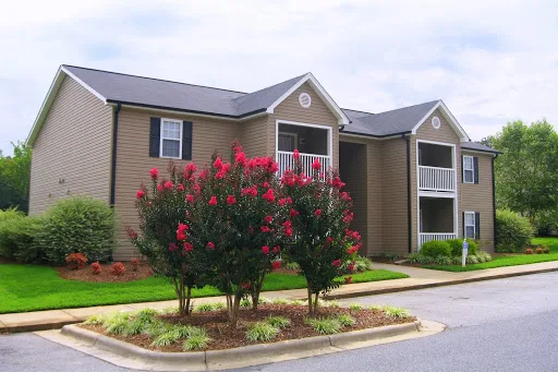 Matthew Grande apartment building with brown siding and flowering trees