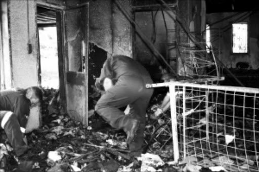 HAVEN DESTROYED: Firemen inspect a room where 11 people perished in a fire.Pic: THULI DLAMINI. 09/02/2010. © Sowetan.