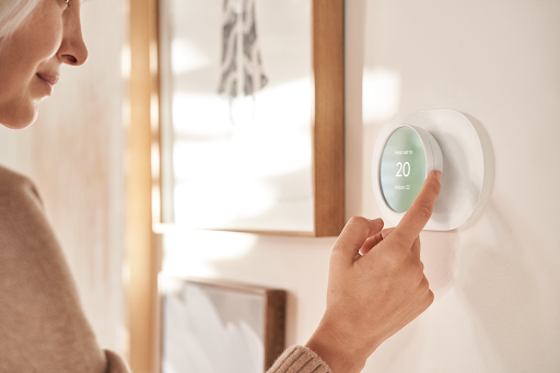 A woman controlling a thermostat