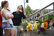 Young women look at floral tributes near the Olympia shopping mall, where yesterday's shooting rampage started, in Munich, Germany July 23, 2016.  REUTERS/Arnd Wiegmann
