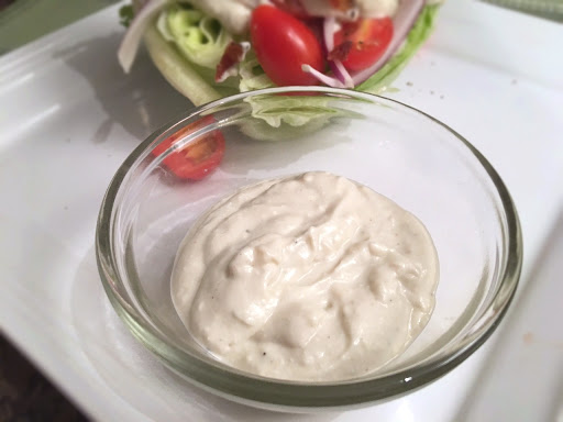 Blue cheese dressing with salad on a white plate.