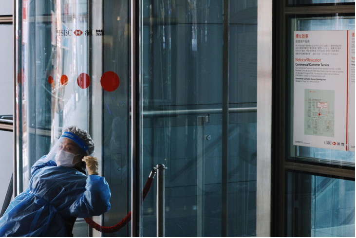 A security personnel in personal protective equipment stretches after HSBC closes its branch at headquarters due to multiple coronavirus disease cases according to media reports, in Hong Kong, China on March 17, 2021.