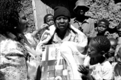 FESTIVE GOODWILL: KwaZulu-Natal first lady Zama Ndebele gives Nomonde Mbambo, centre, a Christmas gift as some of her 21 grandchildren look on. 18/12/08. © Sowetan.