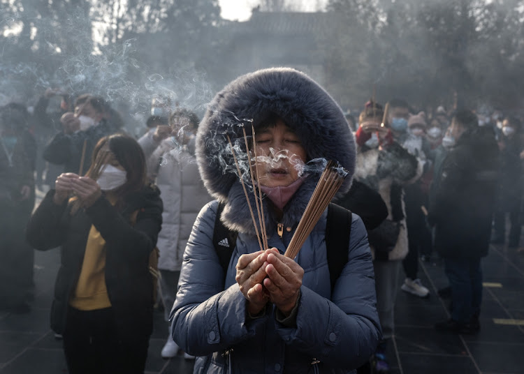A woman holds incense sticks as people perform prayers for good fortune at Yonghegong (Lama Temple) for the Chinese Lunar New Year on January 22 in Beijing, China. They were the first Lunar New Year prayers without restrictions since the pandemic began in 2020, after the Chinese government changed its strict zero Covid policy last month.