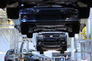 Cradles transport Volkswagen Touran R-Line Sport Utility Vehicles (SUV) on the assembly line at the Volkswagen AG (VW) factory in Wolfsburg, Germany.