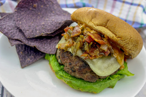 An All American Cajun Burger on a plate with tortilla chips.