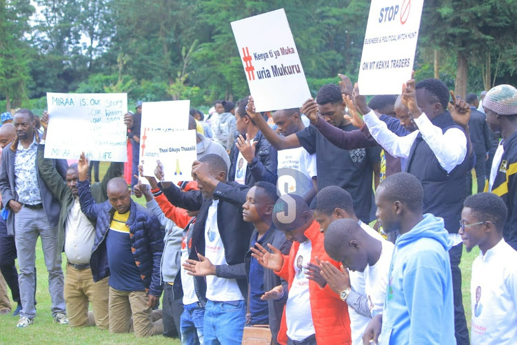 Mt Kenya youth kneel in prayer while holding placards during the Limuru III Conference on May 17, 2024.