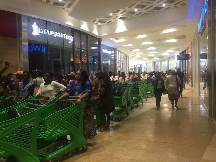 Customers queue at shopping shopping centre for Black Friday deals.