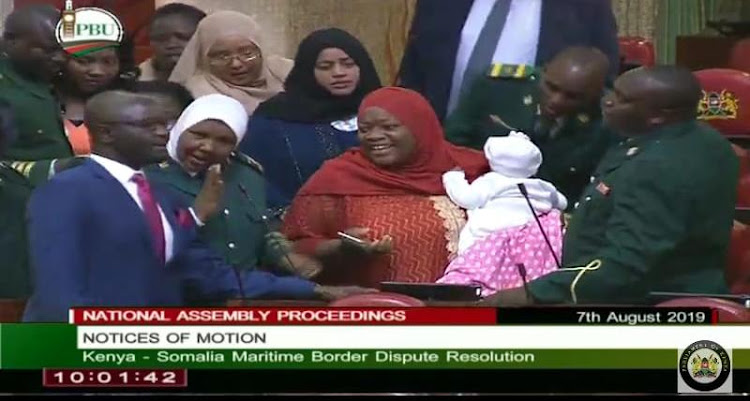 A screen grab showing Kwale Woman Representative Zulekha Hassan being led out of the House chambers by the sergeant-at-arms after she walked in chamber with a baby.