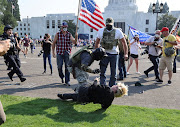 A Black Lives Matter activist falls to the ground during a scuffle with supporters of US President Donald Trump outside the Oregon State Capitol building in Salem, Oregon, US September 7, 2020. 