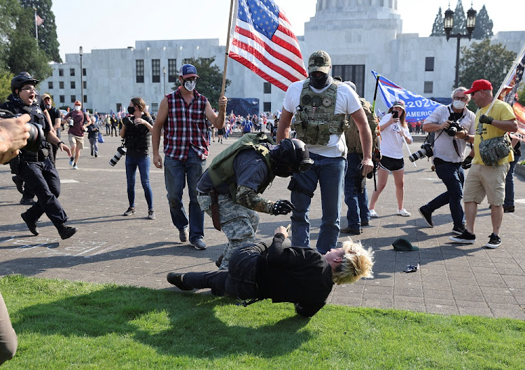 A Black Lives Matter activist falls to the ground during a scuffle with supporters of US President Donald Trump outside the Oregon State Capitol building in Salem, Oregon, US September 7, 2020.