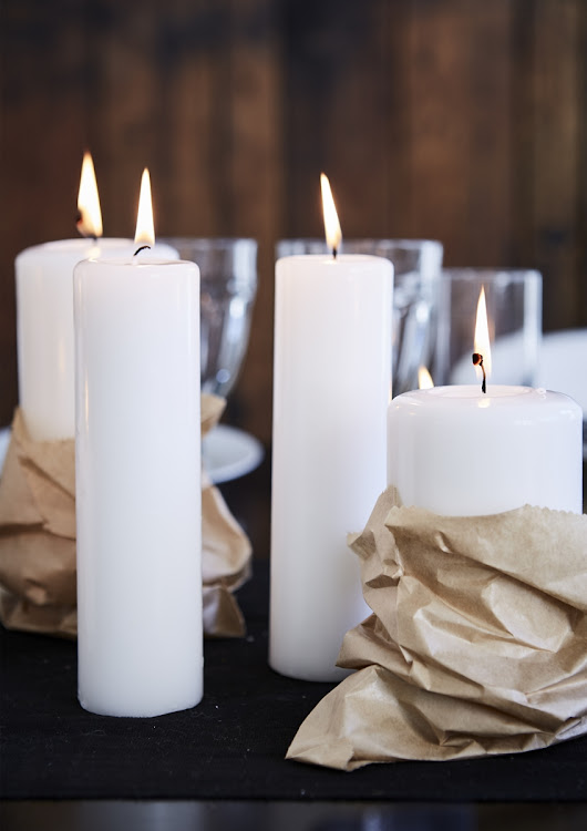 Creative low-cost ideas can have a big visual impact, like these simple white pillar candles wrapped in brown butcher’s paper.