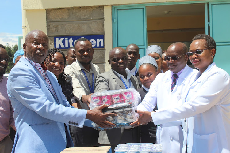 Mukurweini Wakulima Dairy chairman Muhika Mutahi hands over donations of chairs, tables and milk products to Mwai Kibaki Hospital senior director Peter Muiruri and director of clinical and nursing services Juliana Tisnanga in Othaya on September 21, 2022.