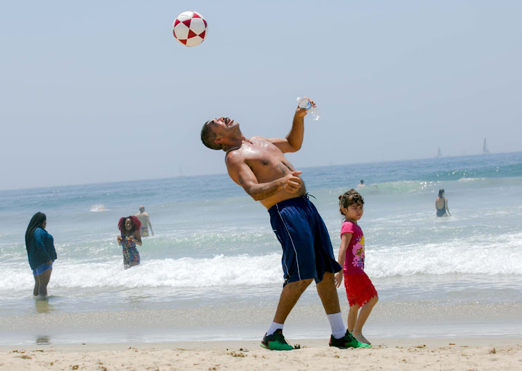 A man balances a soccer ball on Venice Beach in the city of Los Angeles. 