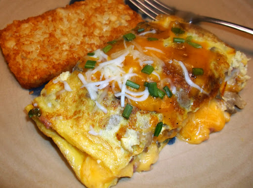 Slice of Mega-Meaty Omelette plated with hash brown patty on side.