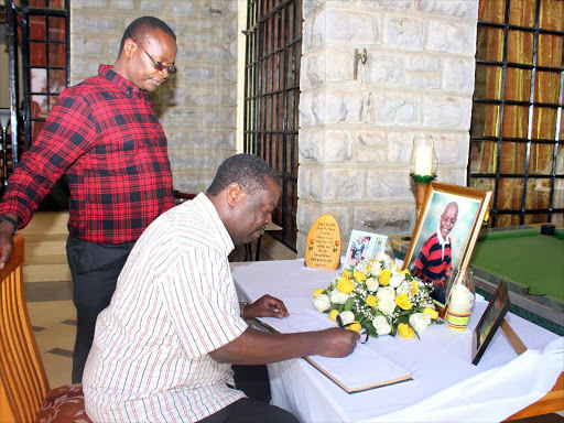 ANC leader Musalia Mudavadi signs the condolence book at Funyula MP Hon. Paul Otuoma(standing) residence when he condoled the family following the death of their Son Malcolm on Saturday.Photo/Ken Andiema