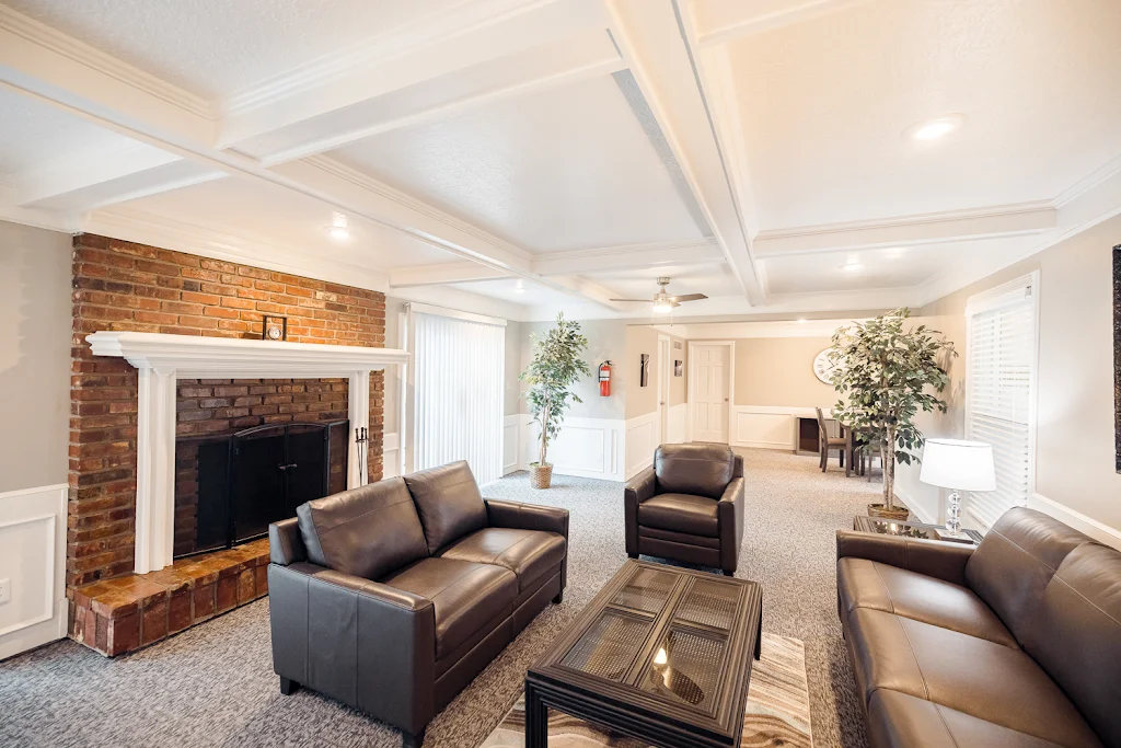 Community leasing office seating area with plush couches, brick fireplace with a white mantle, and decorative accents