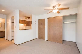 Living room and front door with view to galley kitchen, featuring ceiling fan with light, breakfast bar