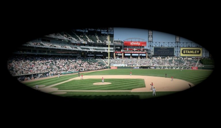 A baseball game as though seen through a telescope with the image in the middle and darkness surounding it.