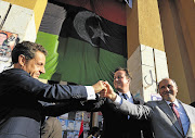 head of Libya's National Transitional Council, Mustafa Abdul Jalil, join hands with France's President Nicolas Sarkozy and Britain's Prime Minister David Cameron in Benghazi.