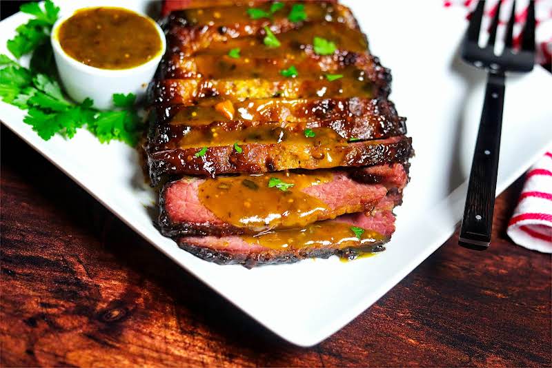 Sliced Brisket On A Plate With Sauce.