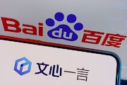 The logo of Baidu's AI chatbot Ernie Bot is displayed near a screen showing the Baidu logo in this illustration.