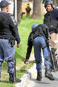 TOOLS OF DESTRUCTION:   Riot police confiscate  a petrol bomb and a flare left behind by protesters in Hout Bay.