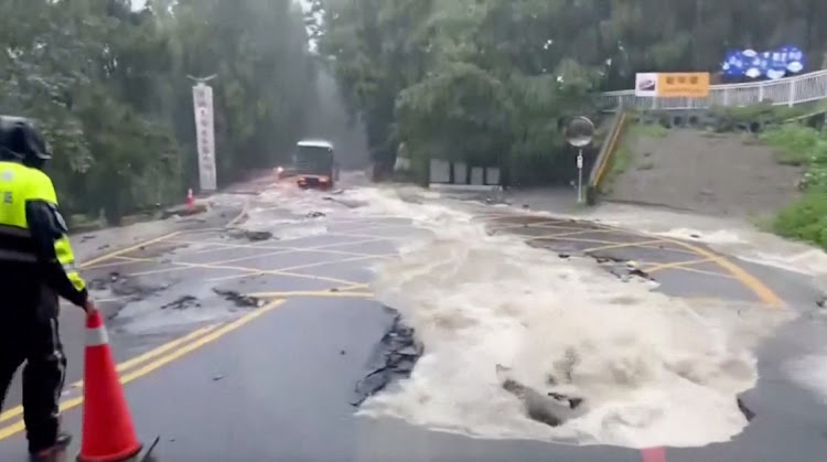 A person stands on a flooded street following heavy rains due to Typhoon Khanun, in Nantou county, Taiwan August 5, 2023, in this screen grab taken from a video provided by CTI. CTI via REUTERS