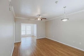 Open living room area with wood inspired flooring, neutral color scheme, and a ceiling fan