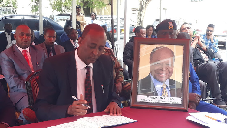 Rift Valley regional commissioner, Maalim Mohamed signs the late President Mwai Kibaki's condolence book outside the regional headquarters in Nakuru on Tuesday.