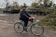 A local resident rides a bicycle past abandoned Russian tanks in the village of Kurylivka, amid Russia's attack on Ukraine, in Kharkiv region, Ukraine October 1 2022. 