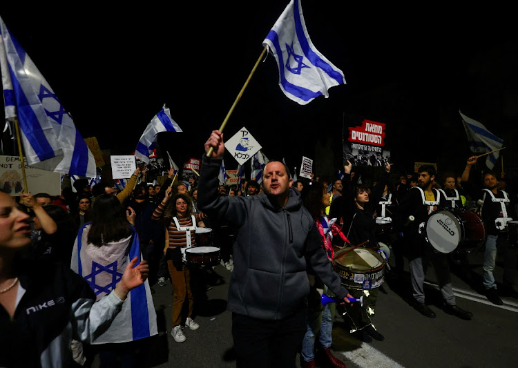 People hold Israeli flags during a demonstration as Israeli Prime Minister Benjamin Netanyahu's nationalist coalition government presses on with its contentious judicial overhaul, in Jerusalem, March 11 2023. Picture: RONEN ZVULUN/REUTERS