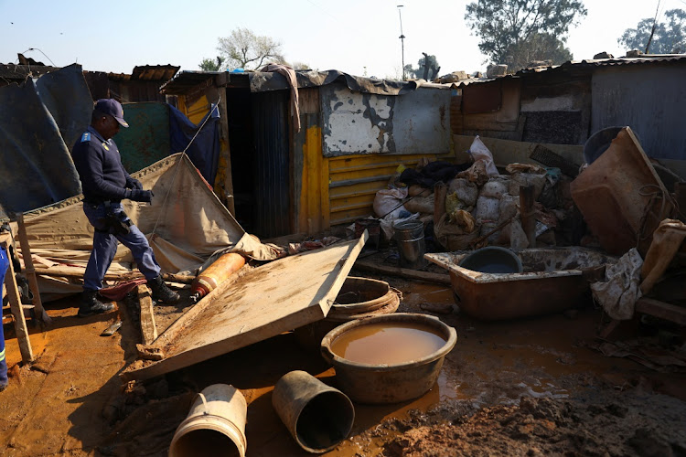 A police officer inspects the site that was used for a makeshift mining operation, at the scene of a suspected gas leak thought to be linked to illegal mining, in the Angelo shack settlement, near Boksburg, east of Johannesburg, on July 6 2023. Picture: REUTERS/SIPHIWE SIBEKO