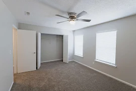 Bedroom with two windows with blinds, brown carpet, light gray walls, closet, ceiling fan, and white trim and doors