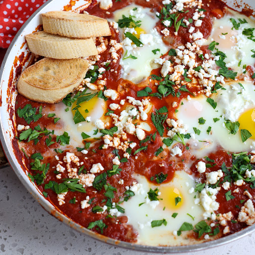 Enjoy this tasty and easy Shakshuka Recipe of eggs poached in a slightly spicy smoky flavorful tomato sauce with onions, garlic, and sweet red bell pepper all topped with fresh parsley and Feta Cheese. 