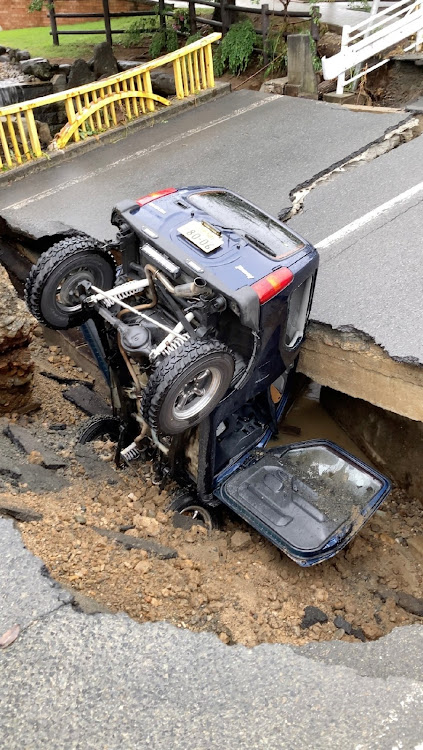 A view of a damaged vehicle on a road damaged by rain in Kawanishi-machi, Yamagata Prefecture, Japan August 4, 2022, in this screen grab obtained from a social media video.